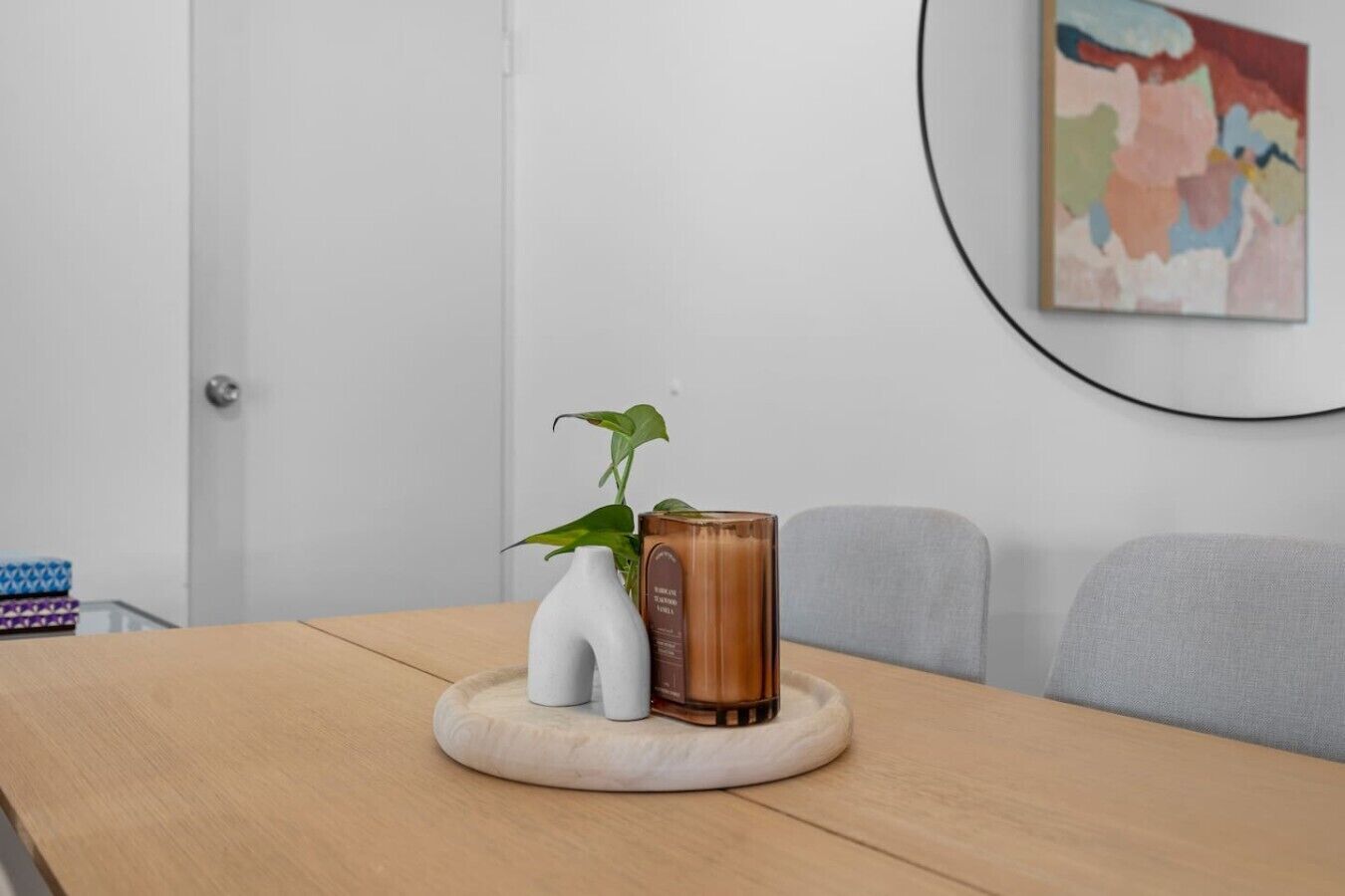 A wooden table with a white vase, a green plant, and a brown container.