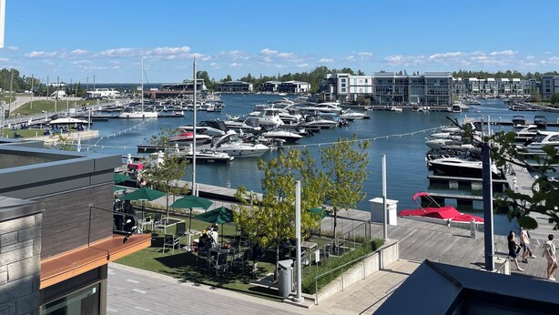 A marina with boats docked, a clear blue sky, and a view of buildings in the distance. - FRIDAY HARBOUR CHIC WATERFRONT GETAWAY (Innisfil)