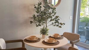 A dining area with a round table, four chairs, a potted plant, and a mirror on the wall. - FRIDAY HARBOUR CHIC WATERFRONT GETAWAY (Innisfil)