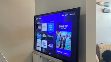 Et fladskærms-tv hængt på væggen, der viser en streamingtjenestes brugerflade med forskellige indholdsvalg.