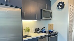 A modern kitchen with stainless steel appliances, dark cabinets, and a wooden floor. - FRIDAY HARBOUR CHIC WATERFRONT GETAWAY (Innisfil)