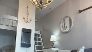 A modern living room with a grey sofa, a wooden bench, a TV, a ladder, and a chandelier. - FRIDAY HARBOUR CHIC WATERFRONT GETAWAY (Innisfil)