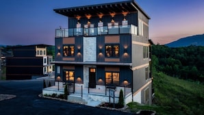 Une maison moderne à plusieurs étages, dotée d’un balcon, d’une allée et offrant une vue sur les montagnes.