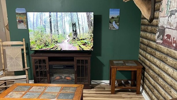 A living room with a television, leather sofas, a wooden coffee table, and a deer head mounted on the wall. - The Buck Lodge | Arcade • Firepit (Wheeling)