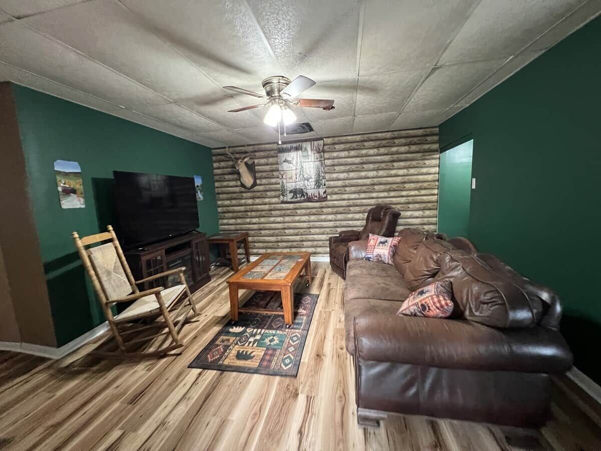 A living room with a brown leather sofa, wooden coffee table, and a television.