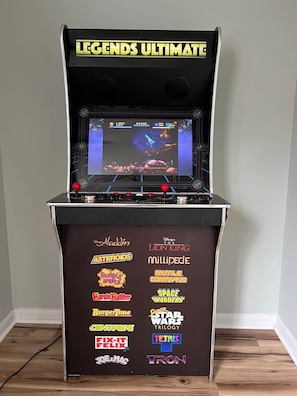 Máquina de salón recreativo con el título 'LEGENDS ULTIMATE', una pantalla mostrando un juego y varios títulos de juegos en el panel frontal.