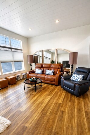 A modern living room with a leather sofa, a black armchair, and a coffee table. - Downtown Lakeview Rooftop Retreat-walk everywhere! (Sandusky)