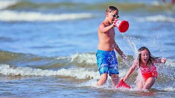 Two children playing in the water at the beach.