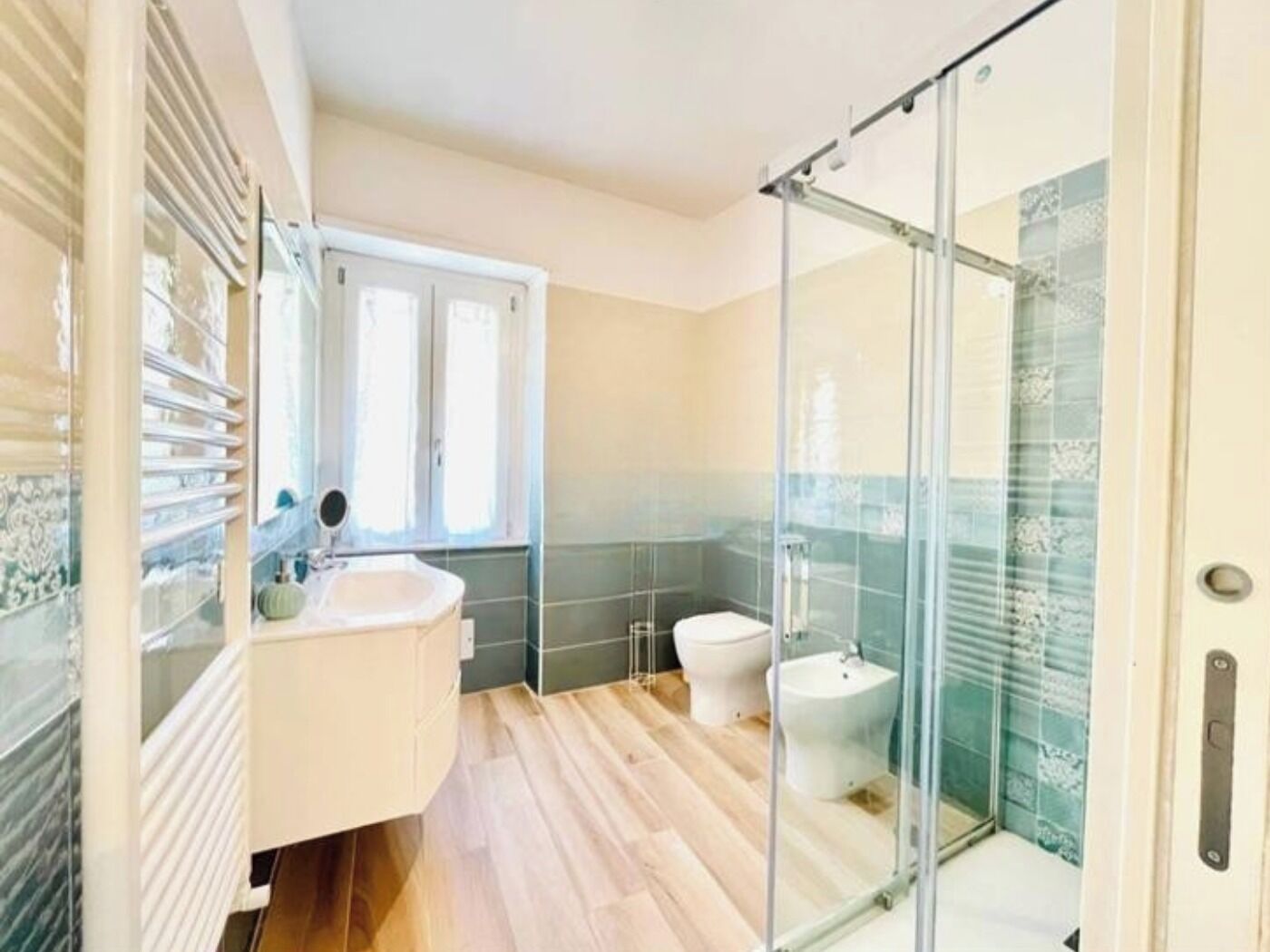 Ein Badezimmer mit Duschkabine, Waschbecken, Toilette und Fenster.