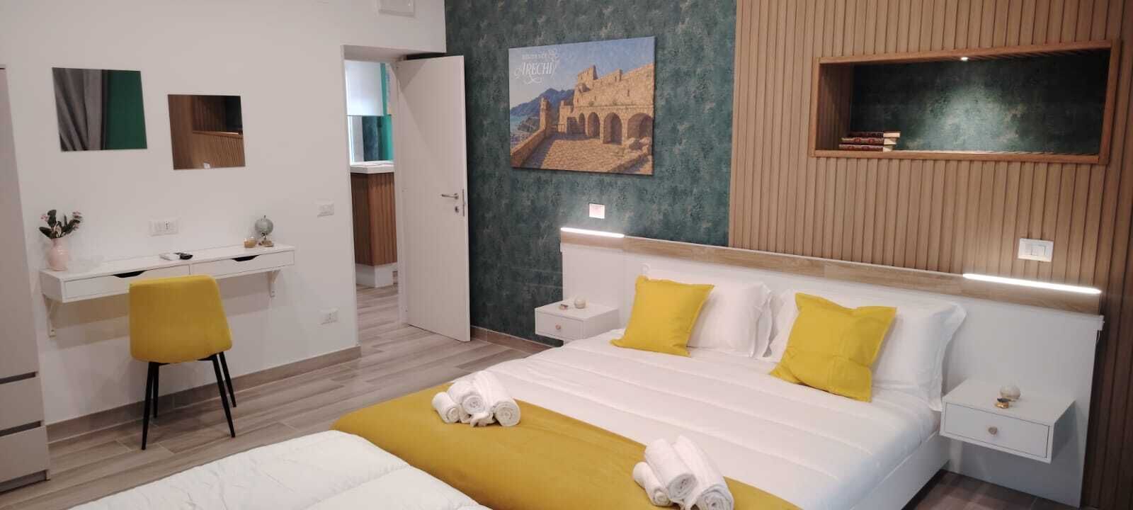 Une chambre d’hôtel avec un lit, des tables de chevet, un bureau, une chaise et un tableau au mur.
