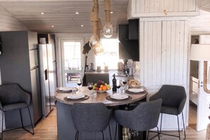 Una cocina moderna con una isla central, taburetes de bar y una mesa de comedor para cuatro.