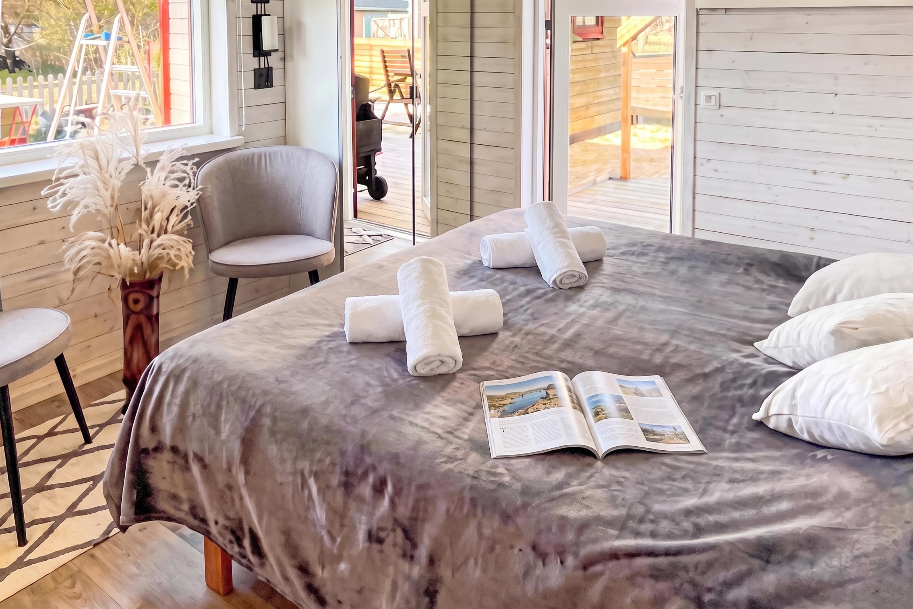 A bedroom with a bed, pillows, a chair, a table, and a window.
