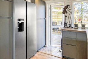 Una cocina moderna con electrodomésticos de acero inoxidable, encimera de madera y un ventanal corredero que da a un espacio exterior.