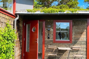 A rustic wooden building with a red door, a window with a sign reading 'S1 James', and a small outdoor seating area with benches. - Skummeslöv Beach Home S, Skummeslövstrand, Sweden (Skummeslövstrand)