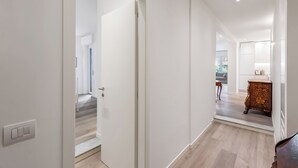 Un pasillo con una puerta blanca, un armario de madera y una escalera que lleva a otra habitación.