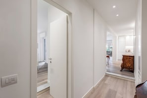 Ein Flur mit einer weißen Tür, einem Holzschrank und einer Treppe, die in einen anderen Raum führt.