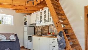 Una cocina con armarios blancos, una escalera de madera y un sofá gris.