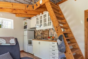 Eine Küche mit weißen Schränken, einer Holztreppe und einem grauen Sofa.