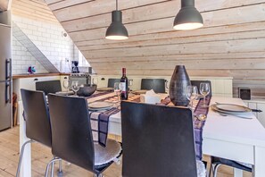 A dining area with a table set for four, chairs, a wine bottle, and a vase.