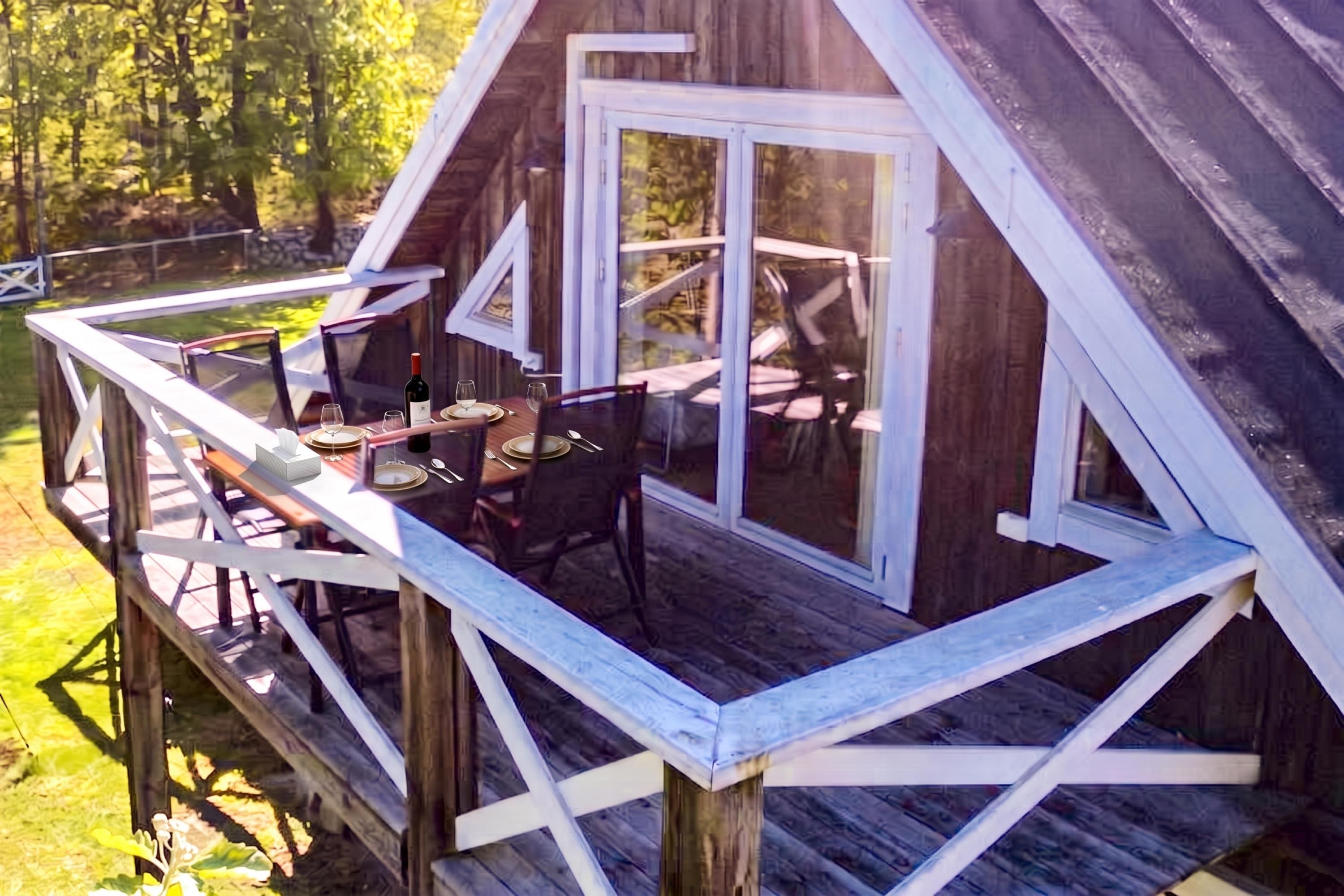 A wooden deck with a dining table and chairs, a glass door, and a view of the surrounding area.