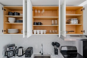 A kitchen with open cabinets, a coffee maker, a toaster, a sink, and a stove. - Blueground | Back Bay West, city view, nr Charles River (Boston)