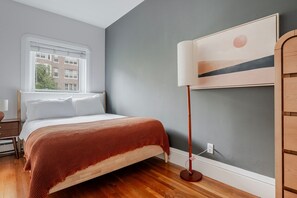 A bedroom with a bed, a window, a lamp, and a wall-mounted artwork. - Blueground | Back Bay West, city view, nr Charles River (Boston)