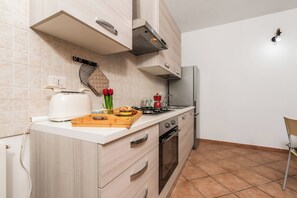 A kitchen with a toaster, a cutting board with food, a kettle, and a stove. - Le Dimore Del Sole, Olbia, Italy (Olbia)