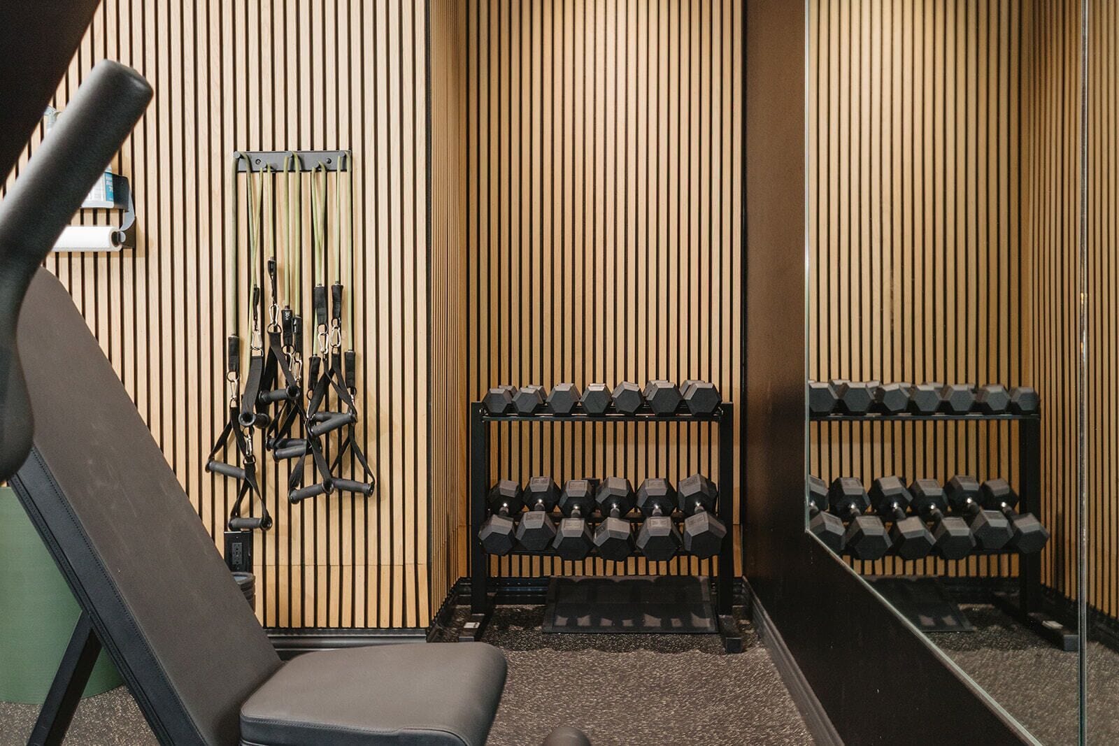 Ett gym med träningsutrustning, inklusive en bänk och hantlar.
