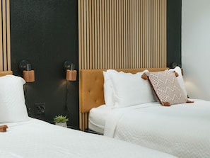 Una habitación de hotel con una cama, una lámpara de pared y una planta pequeña.