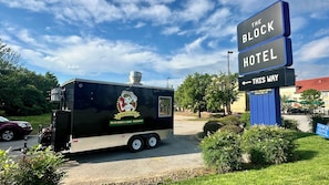 Un camión de comida con un cartel que dice 'The Block Hotel' y una flecha indicando la izquierda.