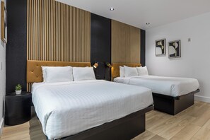Ein modernes Hotelzimmer mit zwei Betten, einem dunklen Kopfteil und einem schwarzen Nachttisch mit Pflanze.