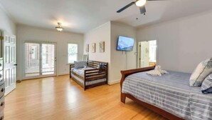 Una camera da letto con un letto, una ventola a soffitto, una televisione e una finestra.