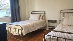 Una camera da letto con due letti a castello in metallo, una ventola a soffitto, un comodino e una finestra con tende.