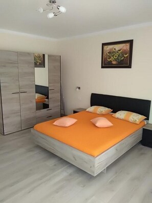 Ein Schlafzimmer mit Bett, Kleiderschrank, einem Gemälde und einer Deckenleuchte.