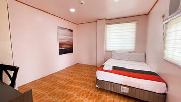 A bedroom with a bed, a window with blinds, a painting on the wall, and a tiled floor.