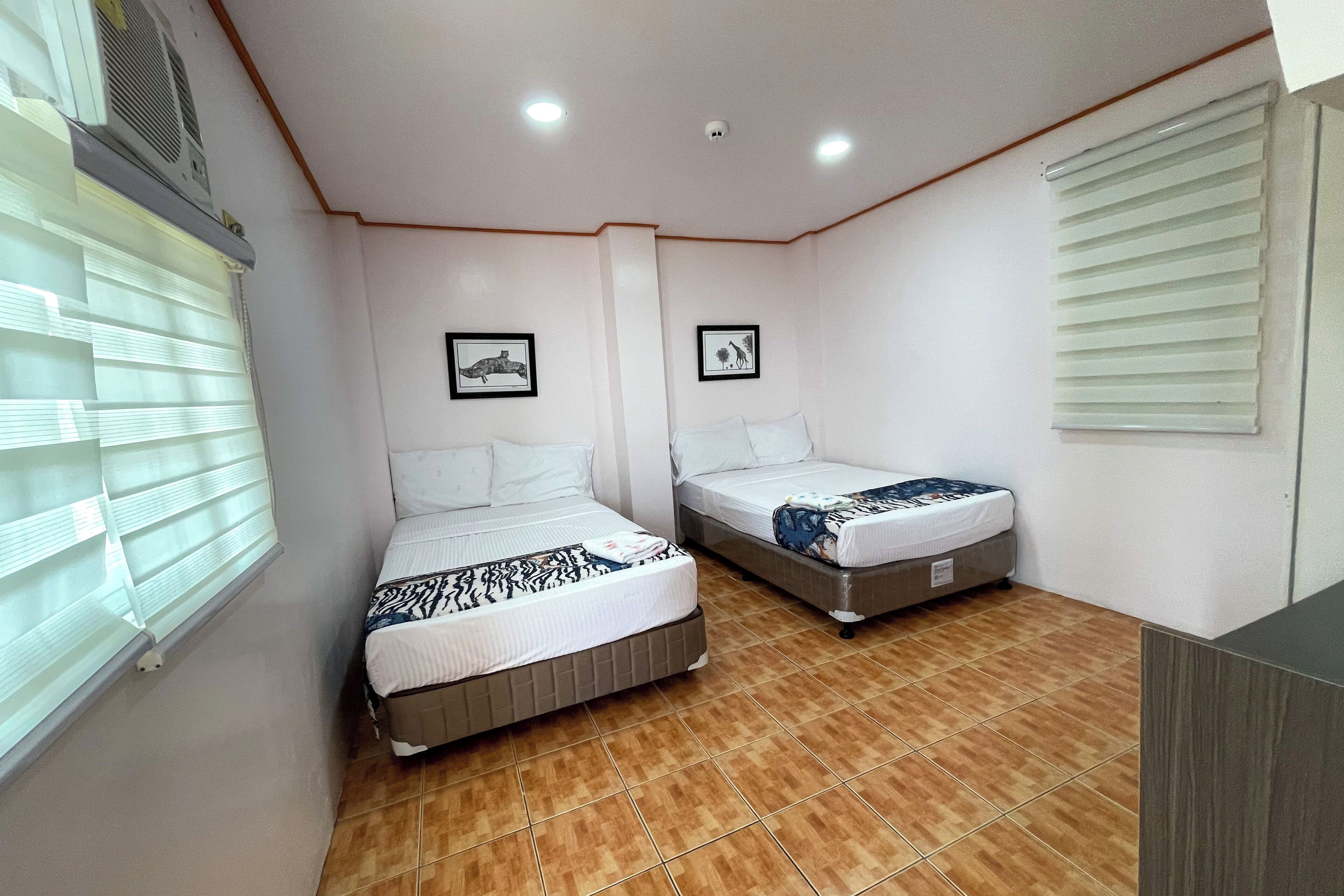 Un dormitorio con dos camas, un ventilador de techo y una ventana con persianas.