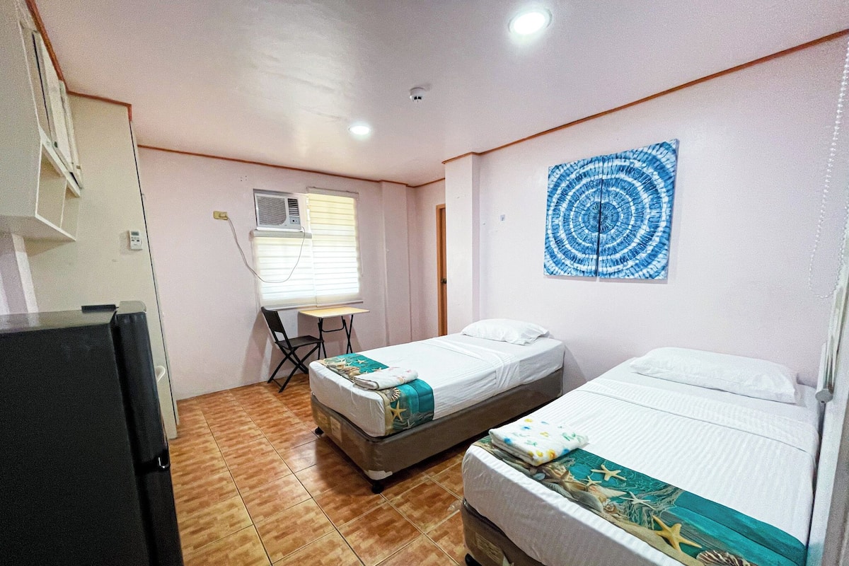 Una habitación con dos camas, un escritorio y un equipo de aire acondicionado.