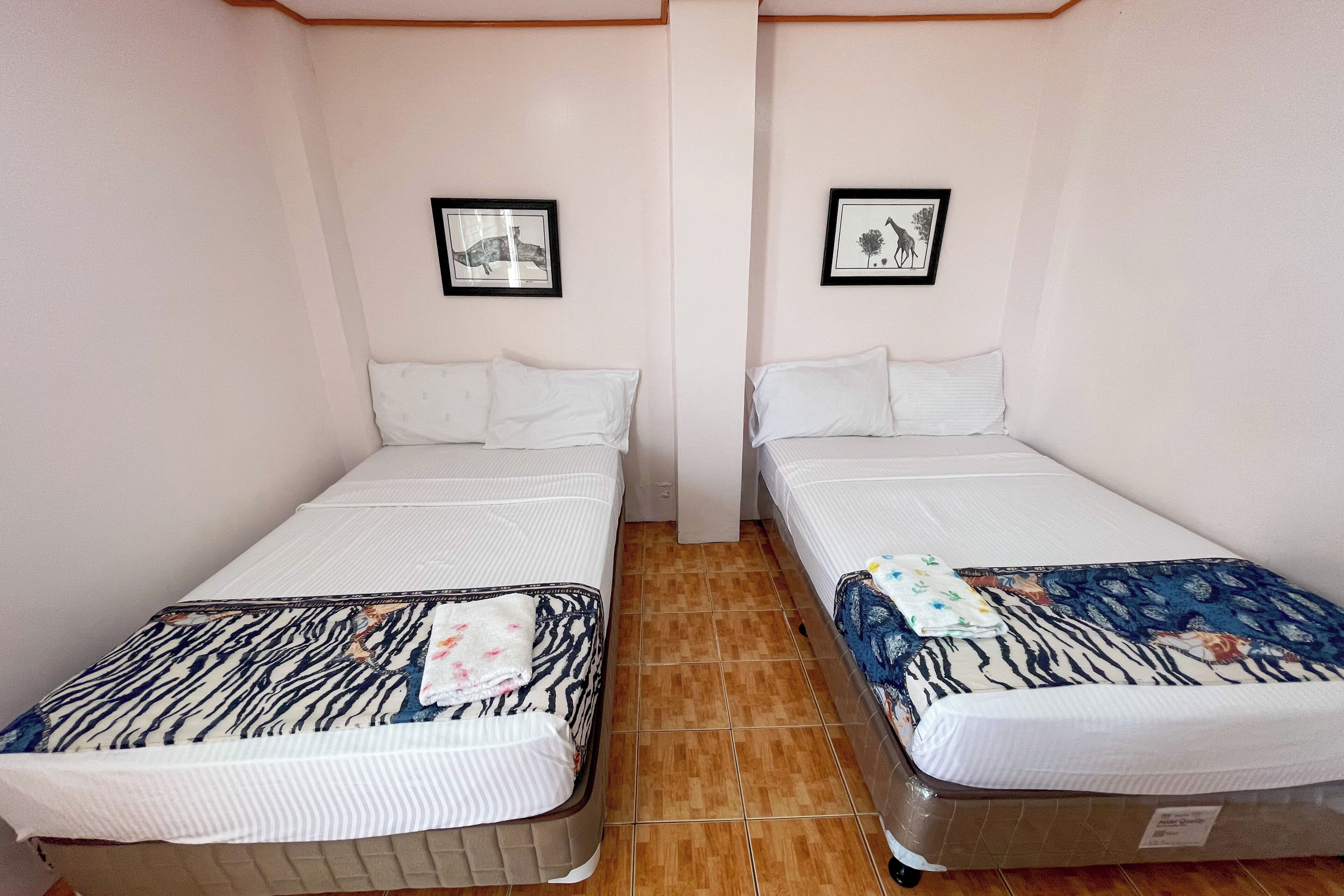 Two single beds with headboards, white bedding, and a tiled floor.