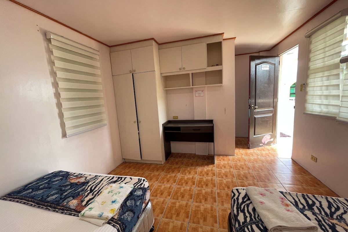 Un dormitorio con dos camas, un escritorio y un armario.