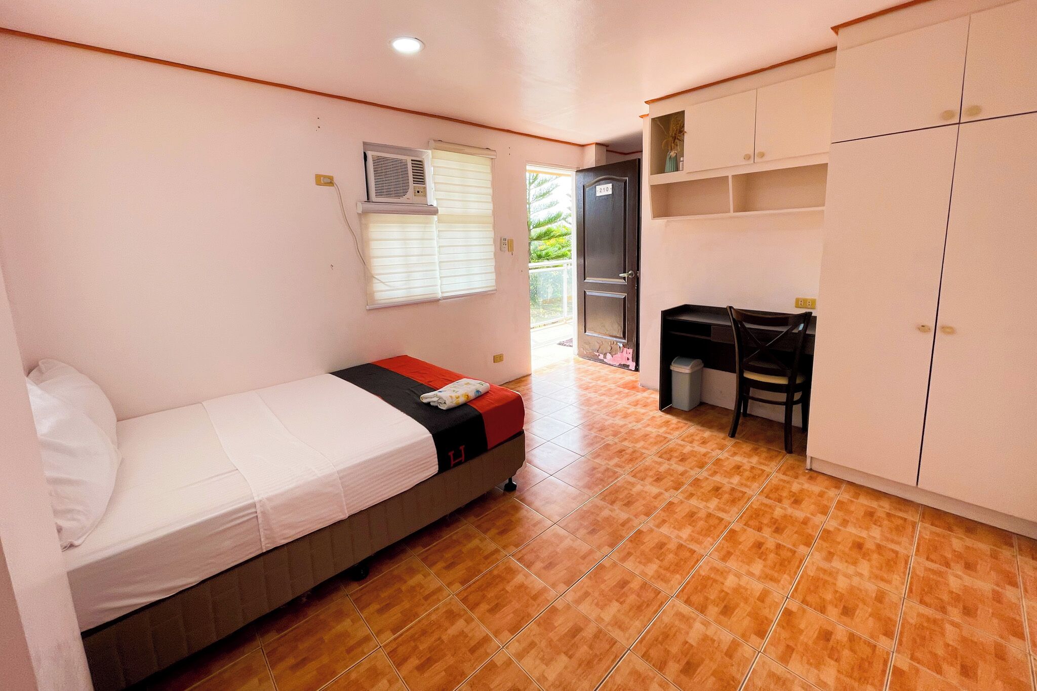 Un dormitorio con cama, escritorio y armario.