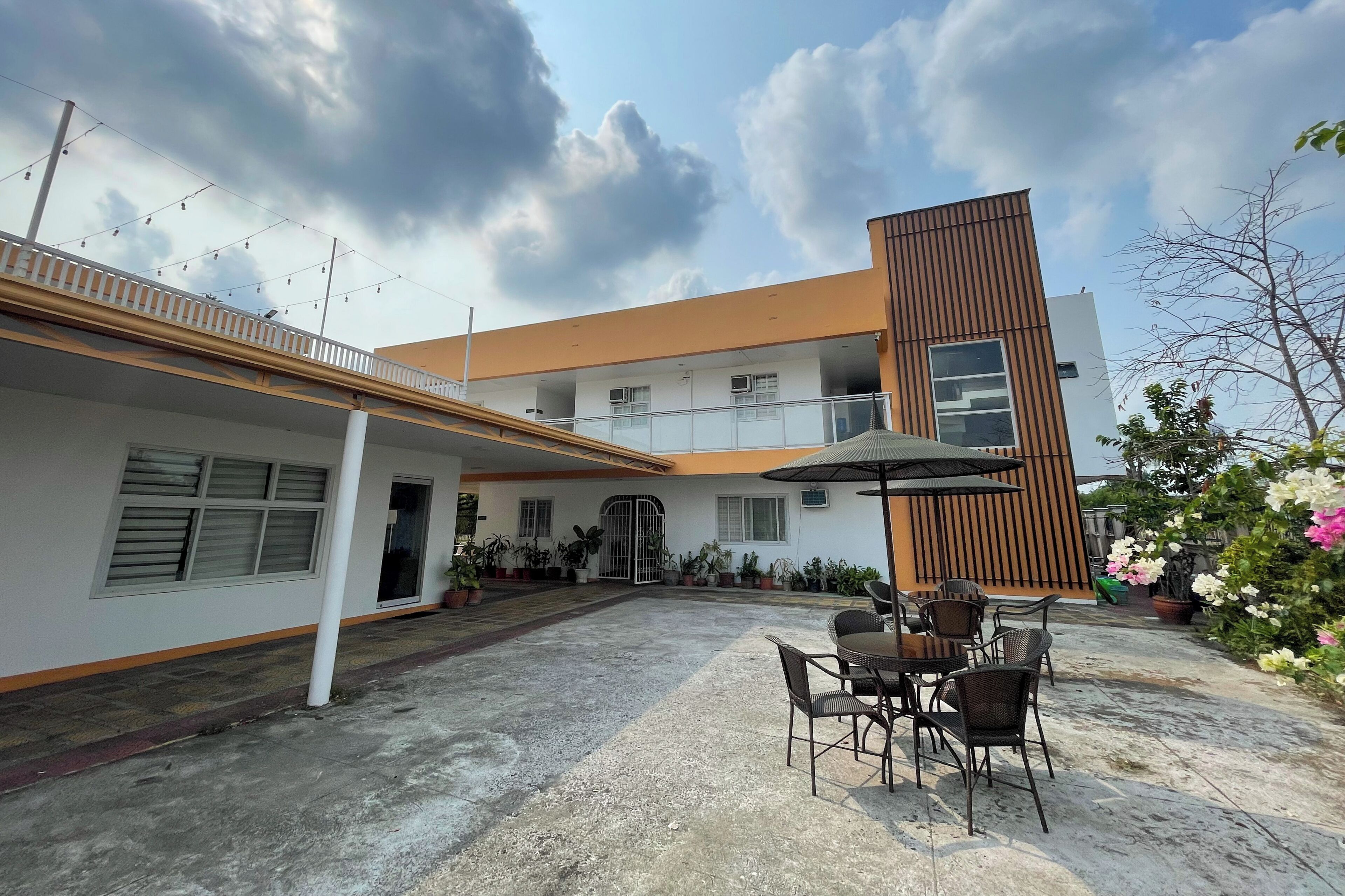 Un edificio moderno con patio, asientos exteriores y plantas en macetas.