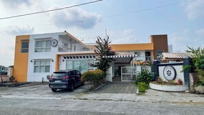 A modern building with a car parked in front, a gated entrance, and a sign indicating a cafe.