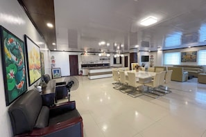 A modern living room with a dining area, a sofa, a fan, and artwork on the walls.