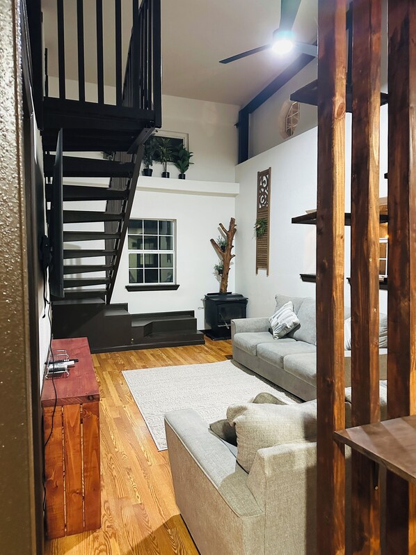 A modern living room with a staircase, a fireplace, and a sofa.