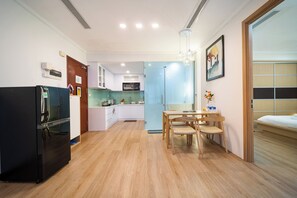 A compact kitchen with a refrigerator, a dining table with chairs, a microwave, and a sink. - IMPERIAL JADE SUITES at LANCASTER (Sai Gon)