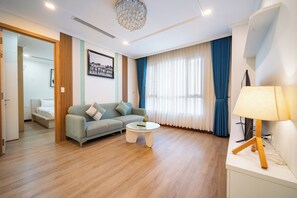 A modern living room with a sofa, coffee table, and lamp. - IMPERIAL JADE SUITES at LANCASTER (Sai Gon)