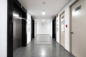 A hallway with elevators, doors, and a fire alarm. - IMPERIAL JADE SUITES at LANCASTER (Sai Gon)