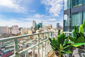 A cityscape with modern buildings and a balcony with a potted plant. - IMPERIAL JADE SUITES at LANCASTER (Ho Chi Minh City)