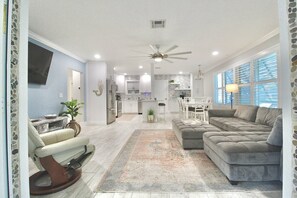 Ein modernes Wohnzimmer mit einer Couch, einem Essbereich und einer Küche im Hintergrund.