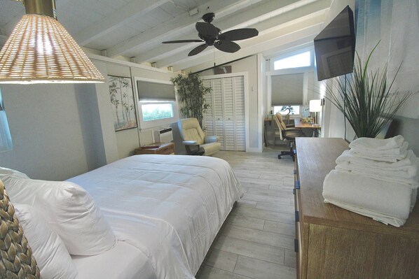 A bedroom with a bed, a ceiling fan, a TV, and a plant. - Lounging Lizard - Downtown Stuart and backyard Sauna (Stuart)